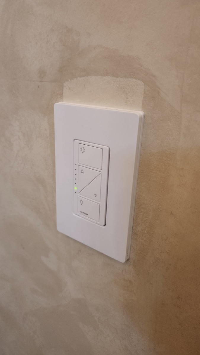 Lutron Caseta dimmer installed on a plaster wall